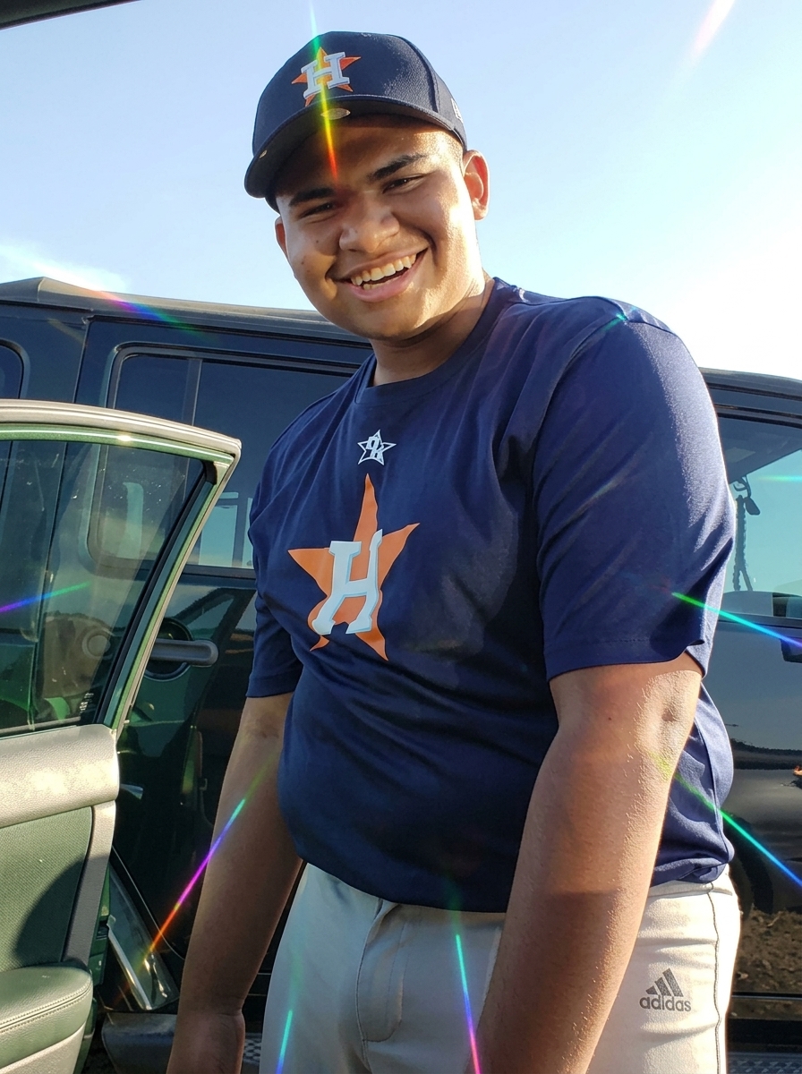 Jaiden smiling in an Astros shirt next to a vehicle