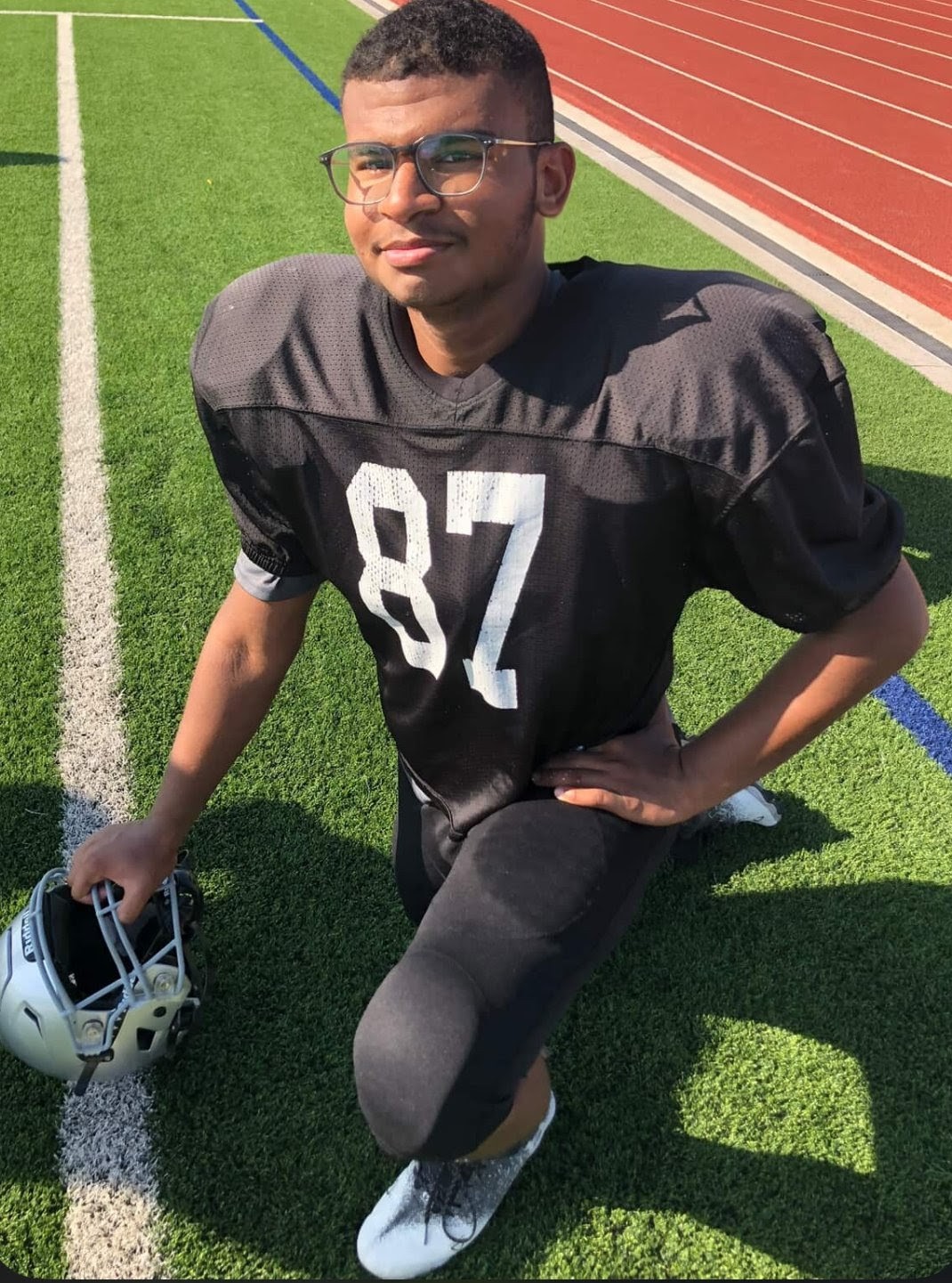 Jaiden kneeling in his #87 football jersey