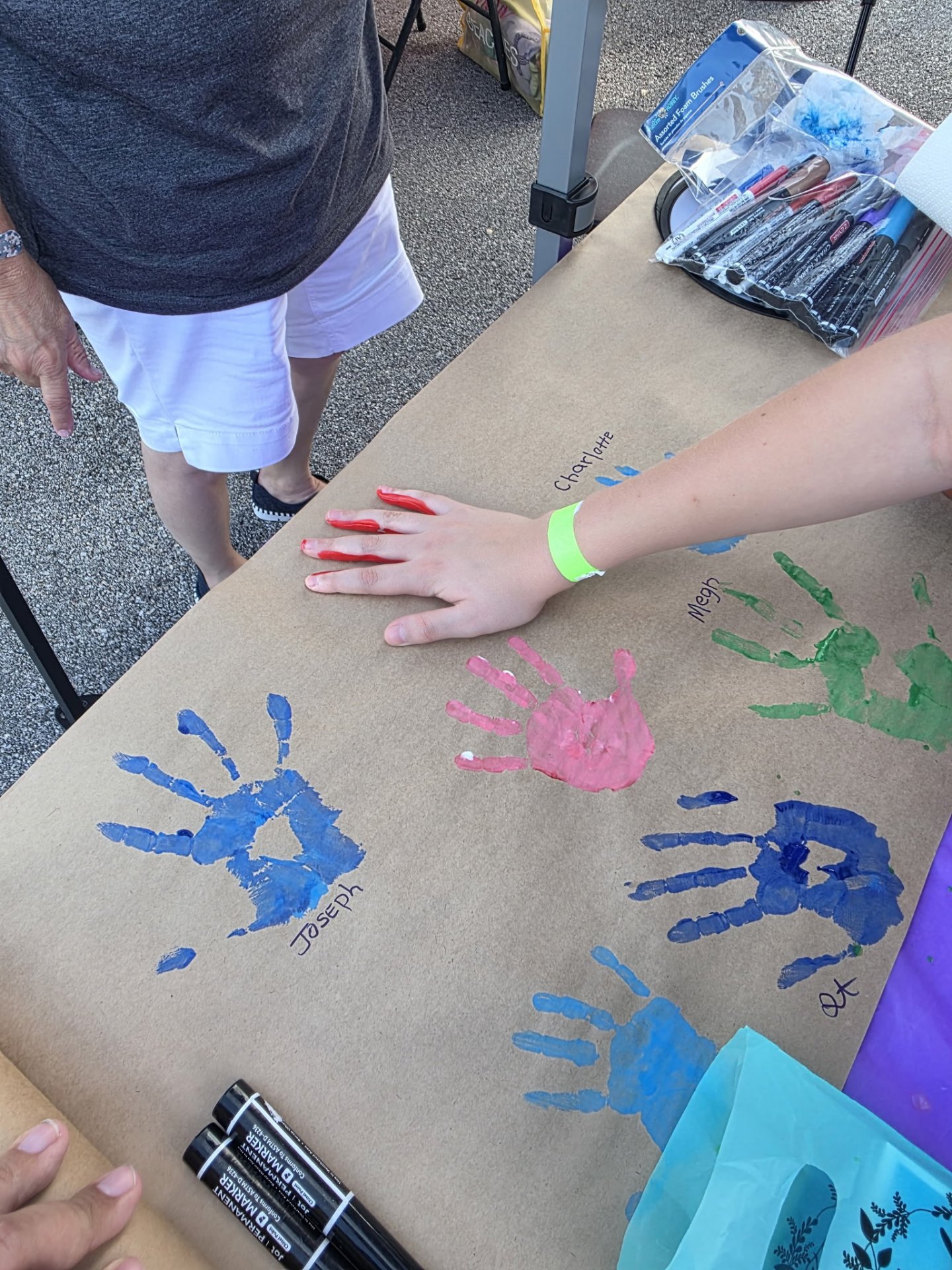 Community members adding painted handprints and names to a banner