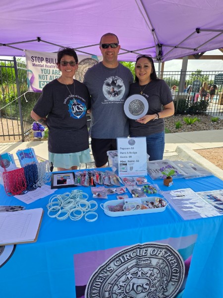 Three JCS volunteers at the foundation booth with giveaways